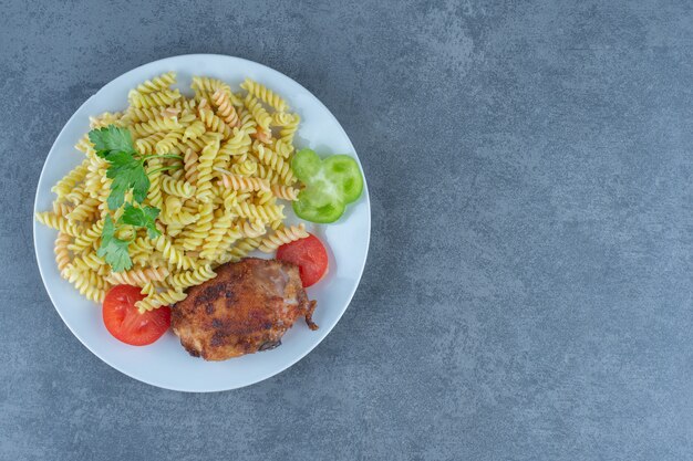 Gebratenes Huhn und Fusilli auf weißem Teller.