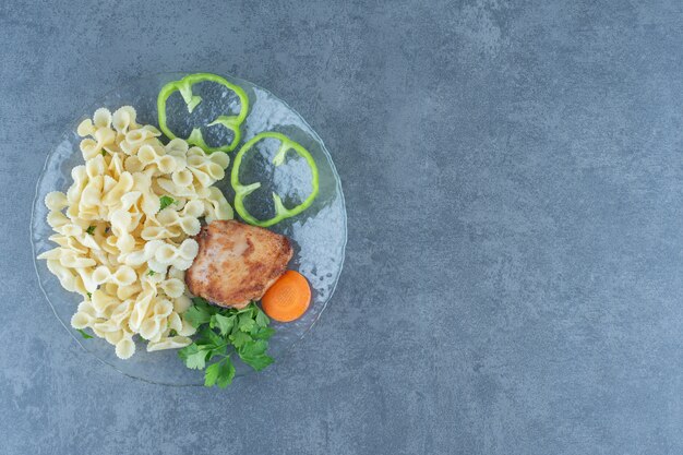 Gebratenes Huhn und leckere Pasta auf Glasplatte.