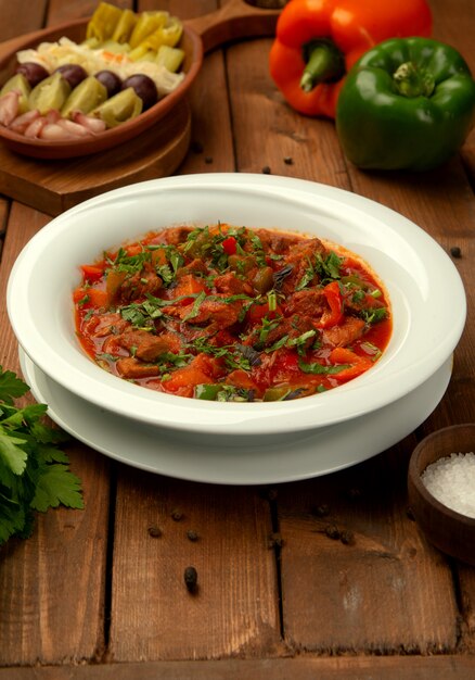 Gebratenes Lammfleisch in Tomatensauce mit Paprika, mit Kräutern garnierte Tomate