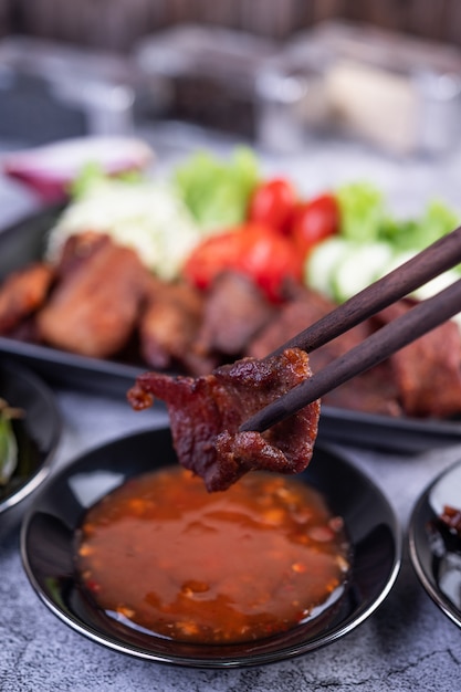 Kostenloses Foto gebratenes schweinefleisch mit sesam in einer schwarzen schüssel.