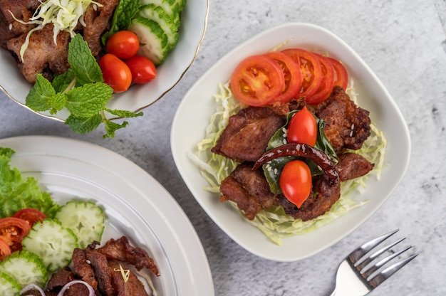 Gebratenes Schweinefleisch mit Sesam in einer weißen Schale.