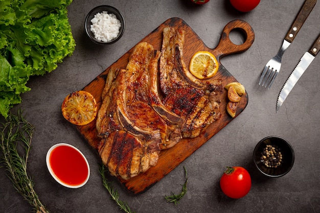 Gebratenes Schweinesteak auf der dunklen Oberfläche.