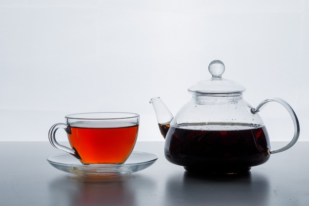 Gebrühter Tee in der Seitenansicht der Teekanne und der Tasse auf einer weißen Gradientenoberfläche
