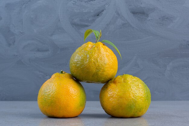 Gebündelte saftige Mandarinen auf Marmorhintergrund angezeigt.
