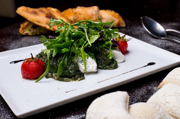 Gedämpfter Spinat mit Seitenansicht der sauren Rucola-Zwiebel-Tomate