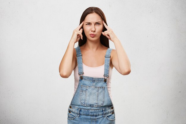 Gedanken, Konzentration und Fokuskonzept. Bild der lustigen jungen kaukasischen Frau in den stilvollen Kleidern, die konzentrierten Blick haben