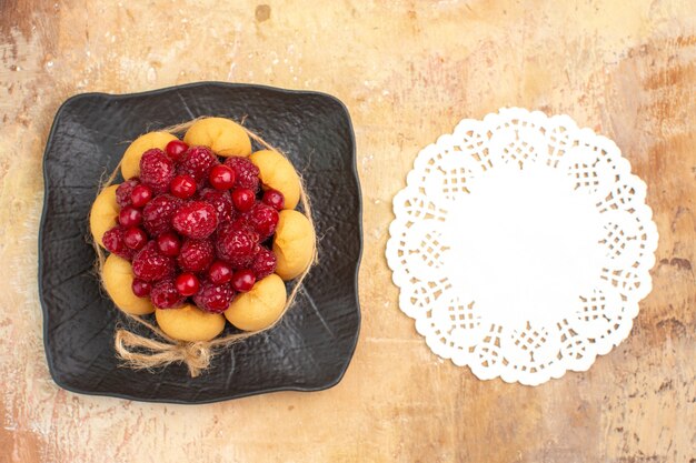 Gedeckter tisch für kaffee- und teezeit mit himbeeren auf kuchen und serviette auf gemischtem farbtisch