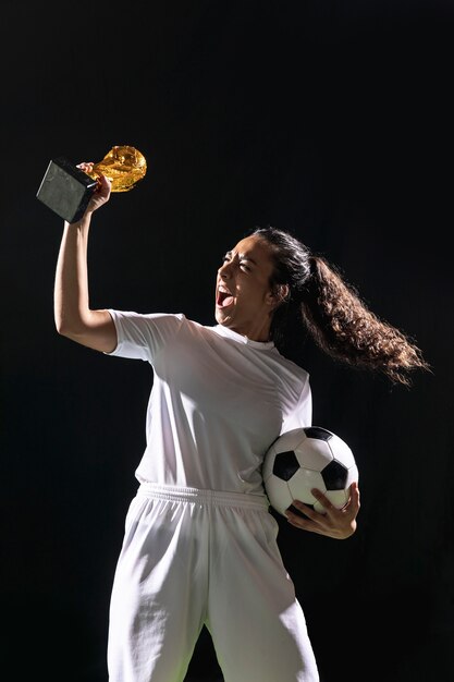 Geeignete Fußballfrau, die Trophäe hält