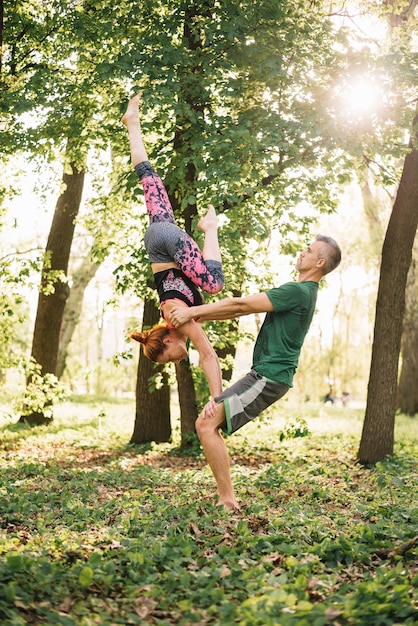 Geeignete mittlere erwachsene Paare, die acroyoga Balance in der Natur tun