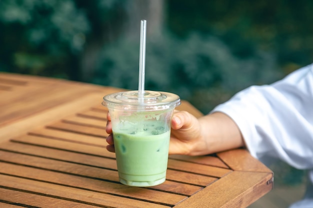 Kostenloses Foto geeister matcha-latte in einem plastikbecher in den händen einer frau