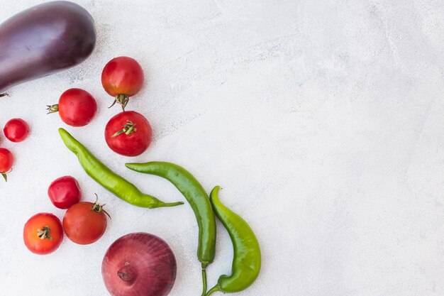 Geerntete Tomaten; grüne Chilis; Zwiebel und Aubergine auf weißem Hintergrund