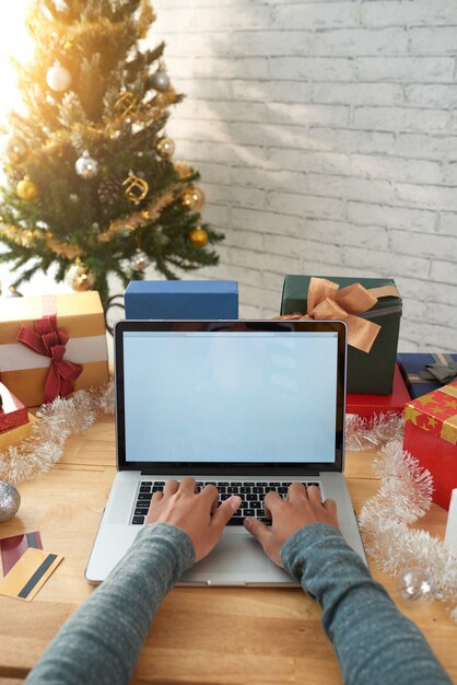 Geernteter Mann, der Onlinekäufe auf Laptop vor Weihnachten abschließt