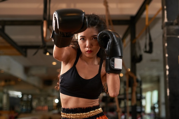 Geerntetes Asiatintraining in den Boxhandschuhen an der thailändischen Praxis Muay