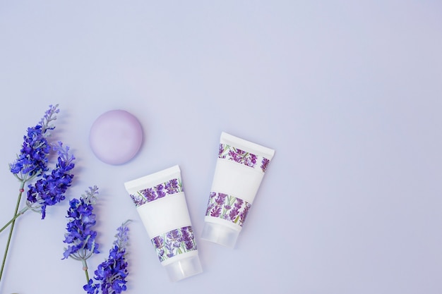 Gefälschte Lavendelblume; Seife und Feuchtigkeitscreme auf farbigem Hintergrund