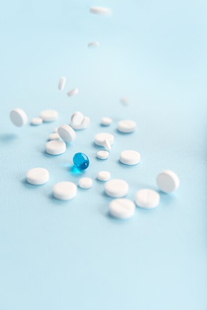 Gefallene weiße Tabletten mit einer isolierten blauen Kapsel