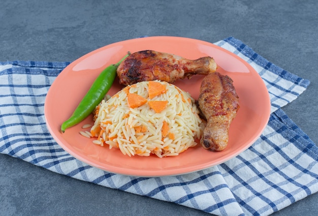 Gegrillte Beine und gewürzter Reis auf orangefarbenem Teller.