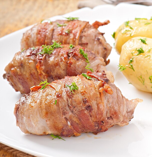 Gegrillte Fleischröllchen in Speckstreifen gewickelt