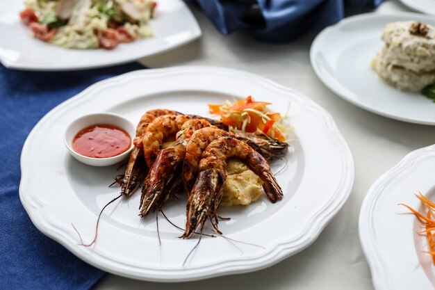 Gegrillte Garnelen von der Seite mit Ketchup und Karotten auf einem Teller