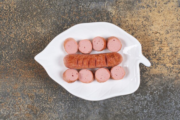 Gegrillte geschnittene Würste auf weißem Blattblatt.