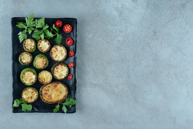 Gegrillte geschnittene Zucchini auf schwarzem Teller.