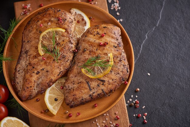 Gegrillte Hühnerbrust auf einem Holzbrett und Gemüse mit Tomaten und Pilzen