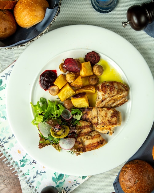 Gegrillte Hühnerbrust von oben mit Kartoffeln gerösteten Kastanien und Gemüsesalat auf einem Teller