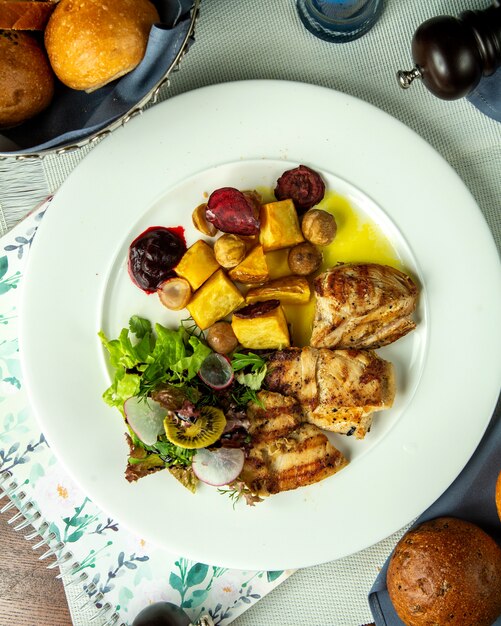 Gegrillte Hühnerbrust von oben mit Kartoffeln gerösteten Kastanien und Gemüsesalat auf einem Teller