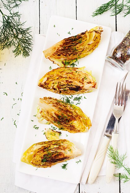 Gegrillte Kohlsteaks des strengen Vegetariers auf weißem Holztisch. Gesundes Essen. Ansicht von oben. Flach liegen