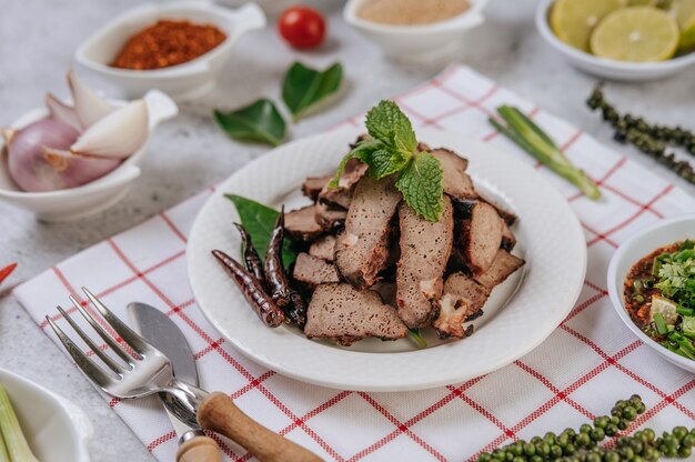 Gegrillte Leberscheiben mit in Scheiben geschnittenen Limetten, Karotten, Chili, Frühlingszwiebeln und Minze.