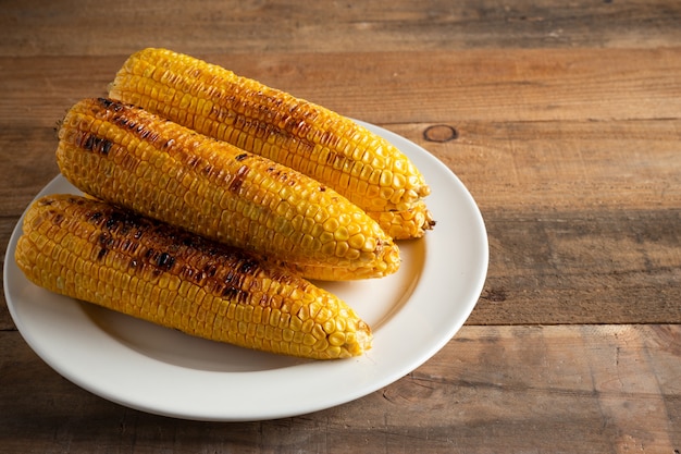 Gegrillte Maiskolben auf hölzernem Hintergrund.