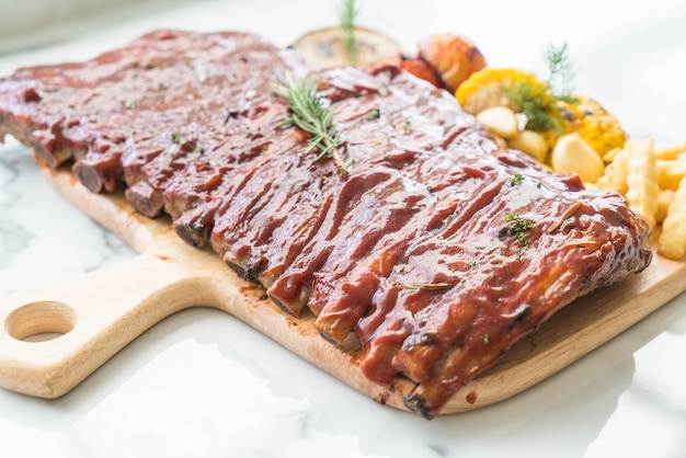 Gegrillte Rippe Schweinefleisch mit Barbecue-Sauce und Gemüse-und Frech-Pommes auf hölzernen Schneidebrett