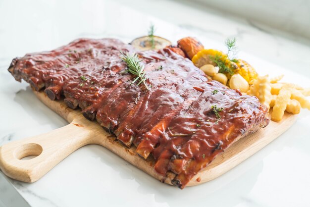 Gegrillte Rippe Schweinefleisch mit Barbecue-Sauce und Gemüse-und Frech-Pommes auf hölzernen Schneidebrett