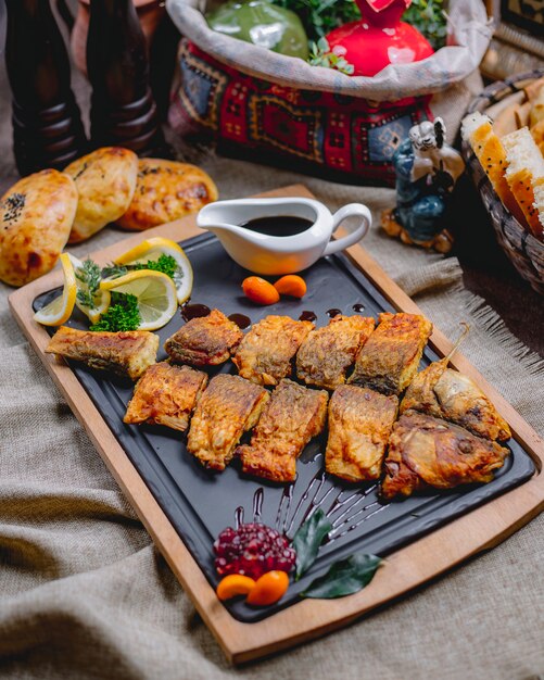 Gegrillter Fisch von der Seite mit Zitronengranatapfelsauce und Brot auf dem Tisch