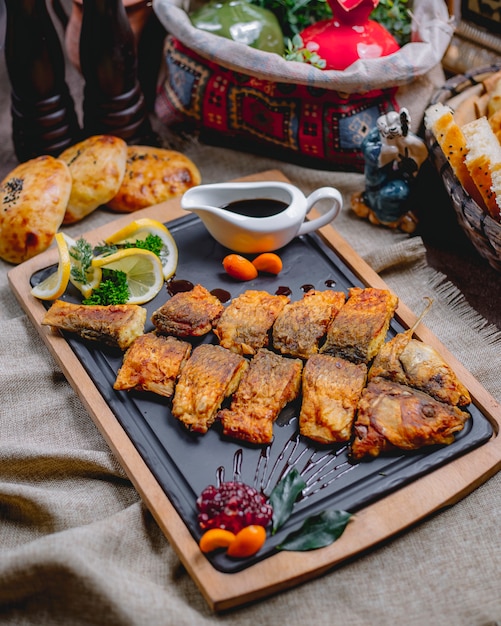 Gegrillter Fisch von der Seite mit Zitronengranatapfelsauce und Brot auf dem Tisch