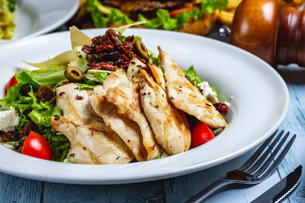 Gegrillter Hickensalat mit Salat Tomaten Tomaten Weißkäse Oliven Gewürzen Seitenansichtjpg