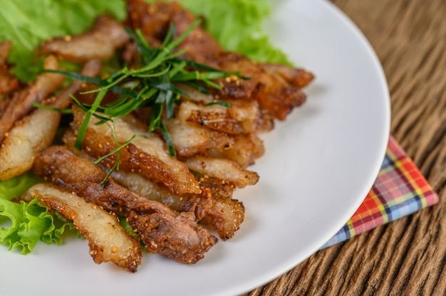 Gegrillter Schweinehals auf einem weißen Teller auf einem Holztisch.