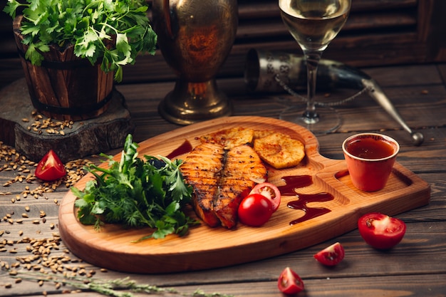 Gegrilltes Fischfilet mit Tomate, roter Sauce, Kräutern und einem Glas Weißwein.