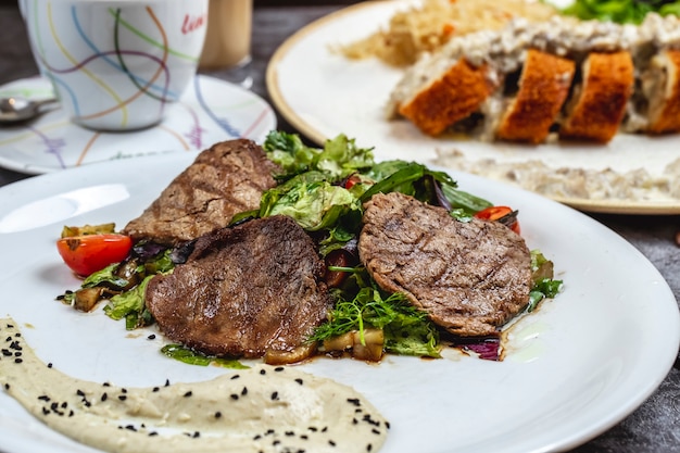 Gegrilltes Fleisch mit Salatpilz-Tomaten-Hummus-Seitenansicht