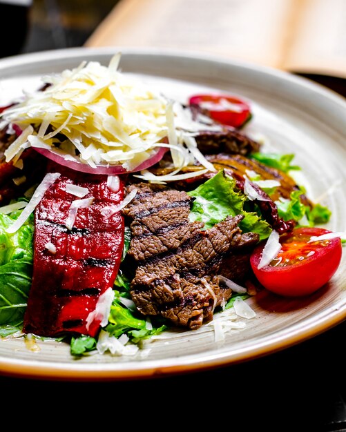 Gegrilltes Fleisch von vorne mit gegrilltem Fleisch mit Gemüse und Salat mit geriebenem Käse auf einem Teller