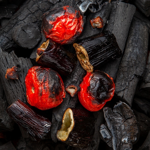 Gegrilltes Gemüse aus Tomaten und Auberginen auf Holzkohle, flach gelegt.