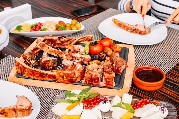 Gegrilltes geschnittenes Lamm auf der Seitenansicht der Holzkartoffel-Tomaten-Pfeffer-Gurken