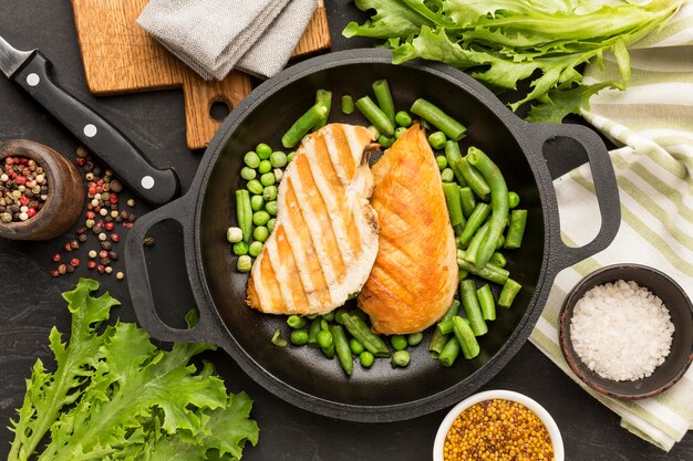 Gegrilltes Hähnchen und Erbsen von oben in der Pfanne mit Gewürzen