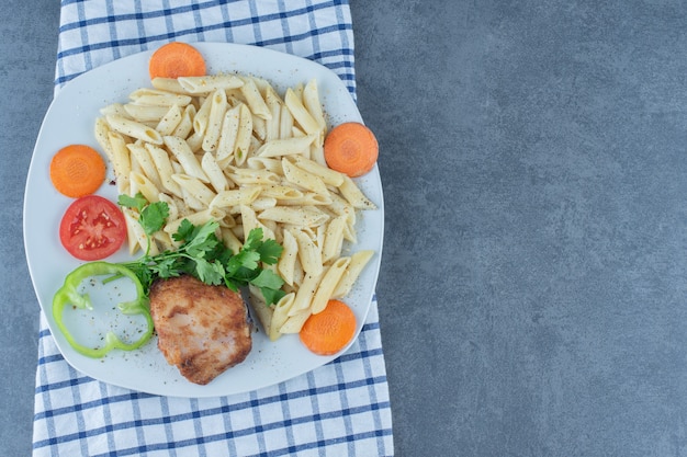 Gegrilltes huhn und cremige penne auf weißem teller.