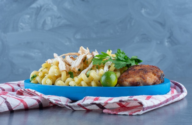 Gegrilltes Huhn und Nudeln auf blauem Teller.