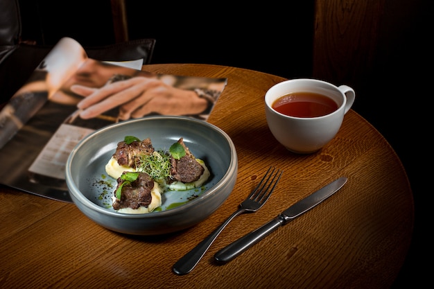 Gegrilltes Steak mit Gemüsepüree auf Teller auf Holztisch.