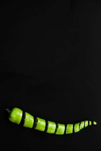 Gehackter frischer grüner Paprikapfeffer auf schwarzem Hintergrund