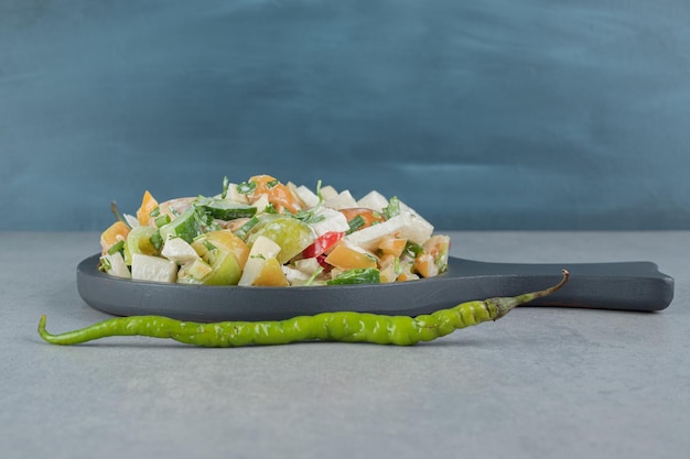 Gehackter Gemüse- und Obstsalat auf einem Holzbrett.