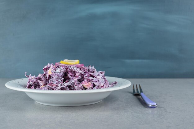 Gehackter lila Zwiebel-Kohl-Salat in einer weißen Keramikplatte.