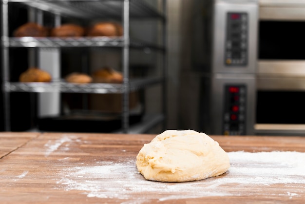 Kostenloses Foto gekneteter teig mit mehl auf tabelle in der bäckerei