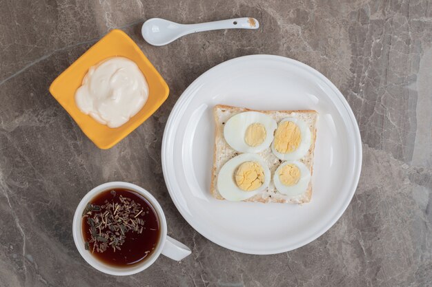 Gekochte Eier mit Brot auf Teller und Tasse Tee. Hochwertiges Foto